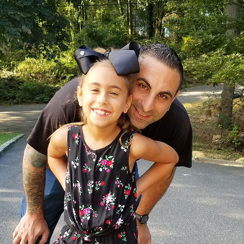 Father and daughter smiling outdoors.