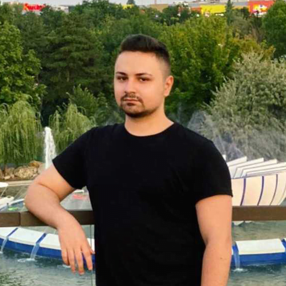Man posing near fountain in park during evening.